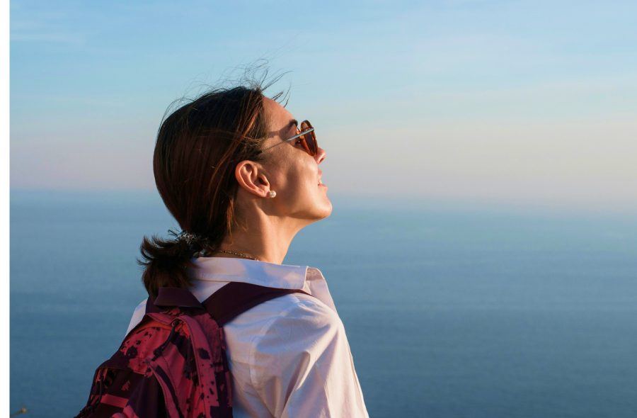 Traveler with backpack overlooking sunset by the ocean